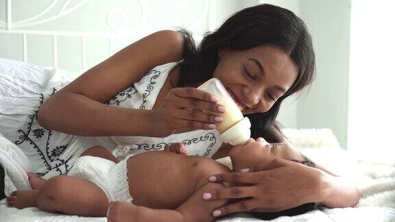 一个非洲小男孩和他的妈妈在床上喝奶瓶里的牛奶
