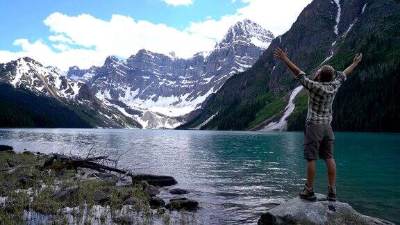 年轻人站在湖边张开双臂拥抱大自然