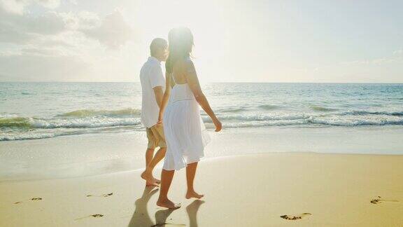 一对情侣在日落时分的海滩上散步