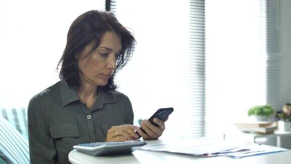 女人在家用智能手机计算财务账单