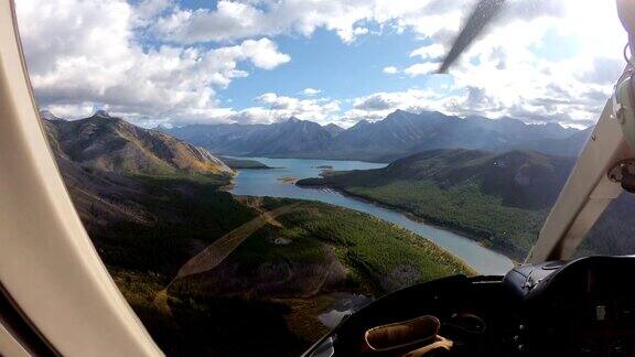 里面的飞行员驾驶直升机在秋季森林与绿松石湖在落基山脉