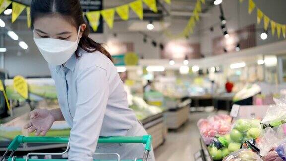 亚洲女孩戴着口罩保护她的脸在超市购物