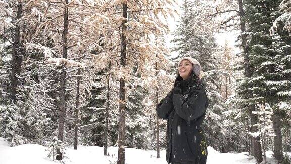 亚洲女人在冬天的森林里享受降雪