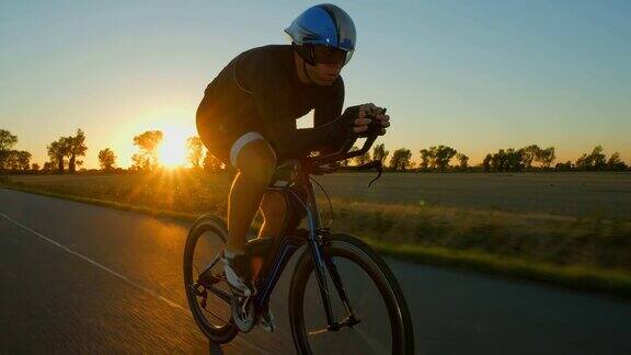 日落日出时一个骑自行车的人在路上使劲地推着车