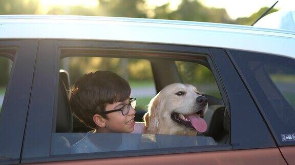 快乐的男孩和她的狗从车窗看
