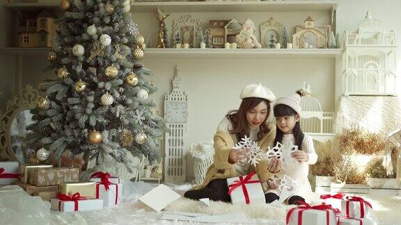 4K快乐的妈妈和女儿在圣诞节玩纸雪花