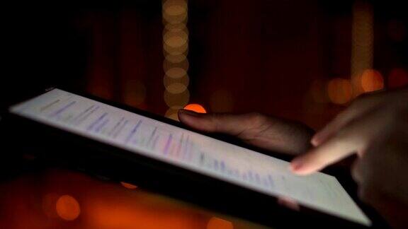 女人的手使用平板电脑触摸屏的特写在夜晚的城市户外搜索