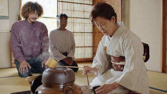 在传统茶道上细心的客人们看着女主人把抹茶从茶盒舀到碗里