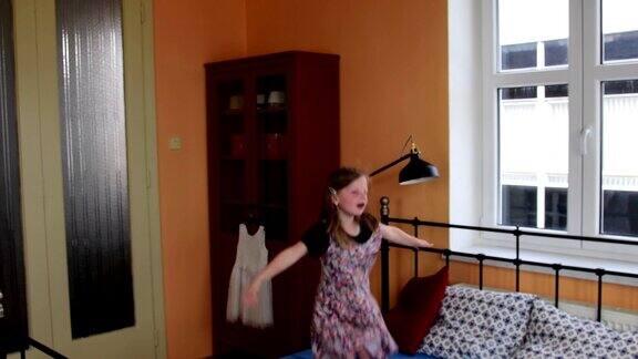 可爱的小女孩在床上又跳又跳小女孩穿着花裙子童年