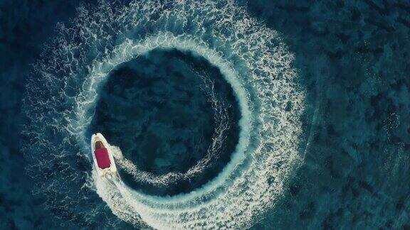 慢镜头航拍下降到一个红色屋顶的快艇在清澈的大海中绕圈做出美丽的形状