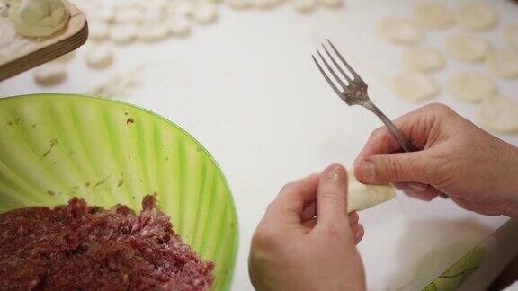 女性手用叉子从大碗里挑肉末然后把饺子馅放进面团里自制的粽子手工制作的