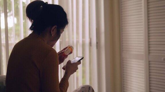 亚洲女性病人在家里用智能手机与医生交谈