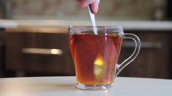 在玻璃杯或马克杯中将糖搅拌并溶解在茶中