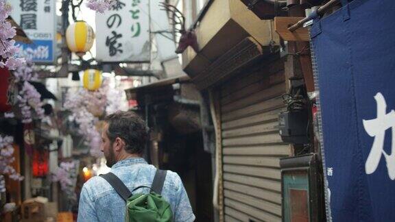 白人男性游客在东京烟雾弥漫的小巷中行走的后视图