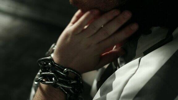 手被铁链锁在牢房里的囚犯