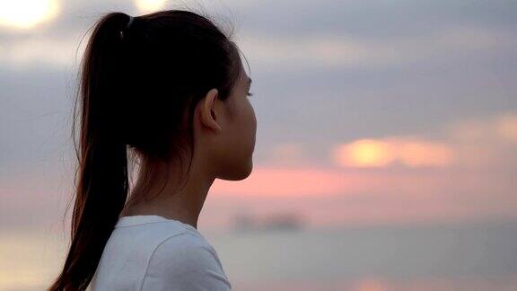 小女孩看着夕阳下的大海背景是海鸥