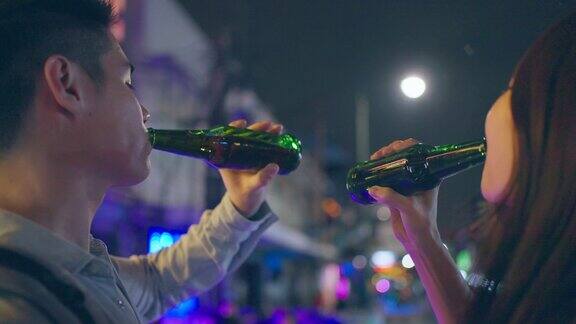 亚洲帅哥情侣一起喝酒开派对在城市旅游的年轻男女在假期的夜晚一起在路上碰碰啤酒