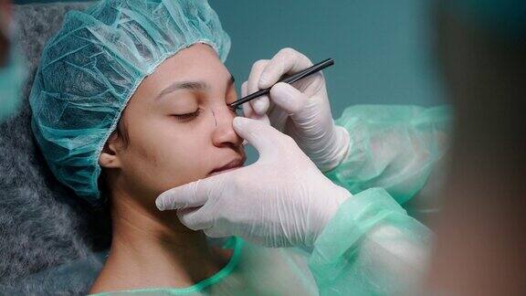 在做鼻整形手术之前外科医生检查了女孩的脸在她的脸上画了画