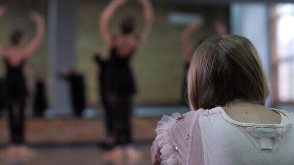 女孩观看芭蕾舞演员在舞厅训练
