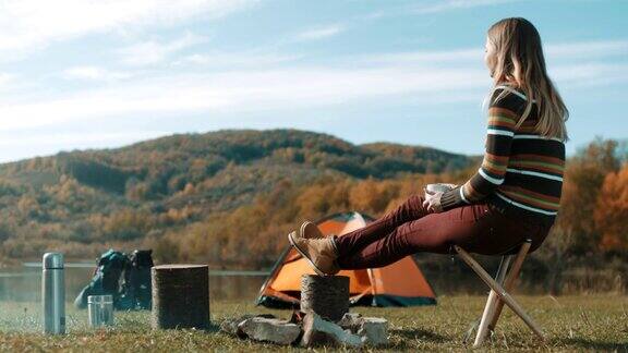 坐在湖边露营喝咖啡的女人