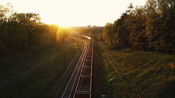 日落时一列货运火车穿过树林航拍