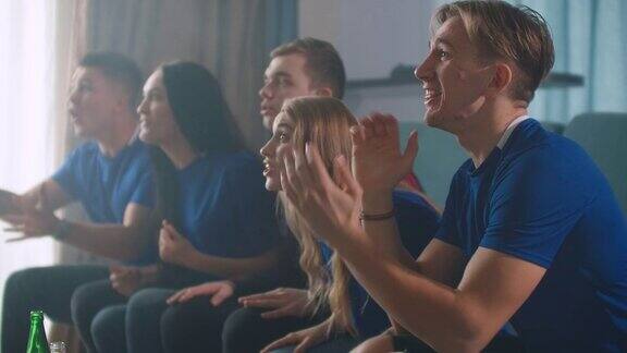 情绪上球迷们在电视上兴奋地观看足球比赛然后坐在沙发上为胜利而欢呼