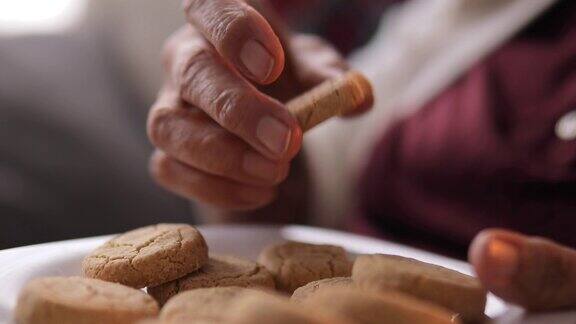 老妇人拿着一盘饼干在家吃着美味的饼干