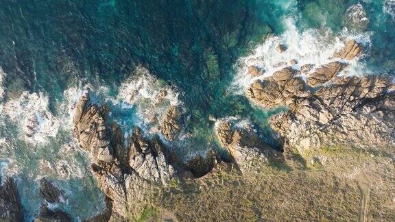 鸟瞰在岩石海岸飞溅的泡沫海浪