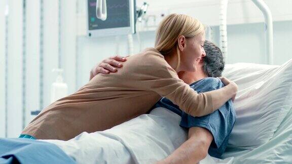 妻子到医院探望躺在病床的丈夫并和丈夫拥抱