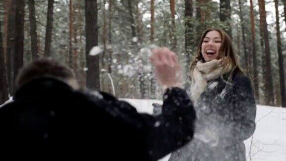在一片冰雪覆盖的森林里一对男女正在互相扔雪球