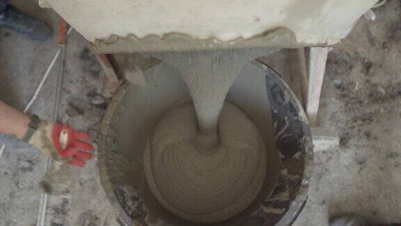 在混凝土搅拌机中搅拌砂浆用沙子和石头搅拌混凝土溶液从混凝土搅拌机中倒入桶中填地板的过程
