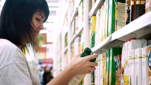 女人在超市挑选果汁在购物中心选购商品的女人女孩站在商店货架旁边挑选商品