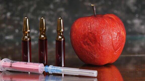 有皱纹的红色苹果与注射器特写