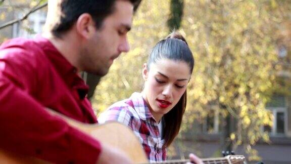 一对夫妇在公园里玩得很开心唱歌和弹吉他