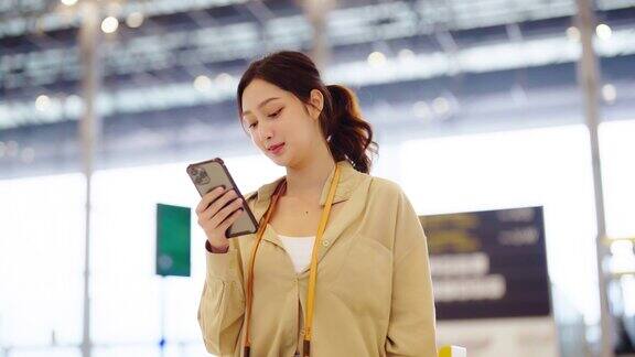一名亚洲女子在机场等待离境亚洲女乘客站在候机大厅用手机等航班