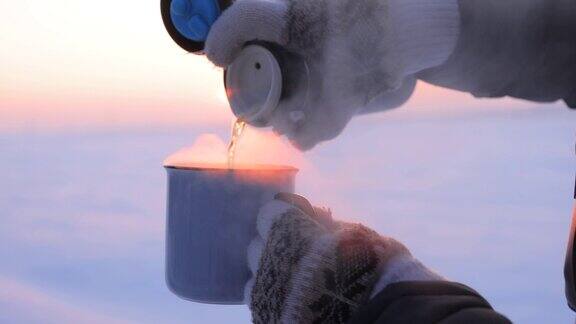 在寒冷的冬天把热水瓶里的茶倒进杯子里
