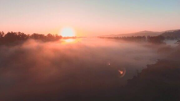 风景飞行穿过浓雾躺在田野和森林朝着太阳