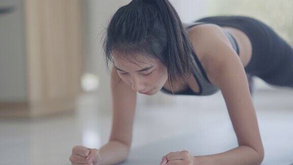 亚洲女人做瑜伽运动与平板姿势在卧室而从在线课堂老师观看