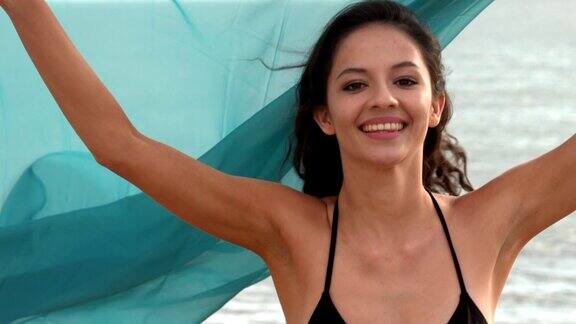 抱着围巾在海滩上跑的快乐女人