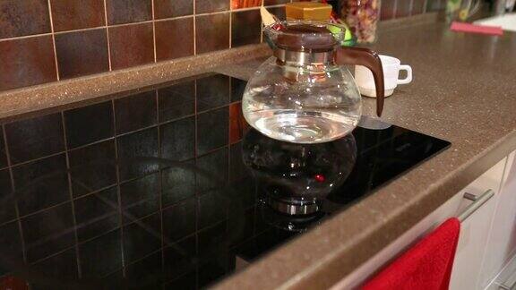 电磁炉上的水壶炉子上的玻璃茶壶男人把水壶放在炉子上