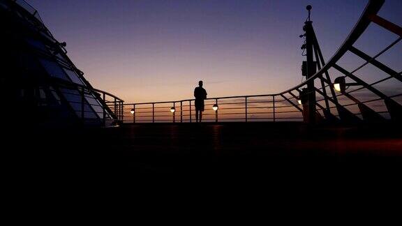 日落时分一名男子的剪影走在游轮甲板上