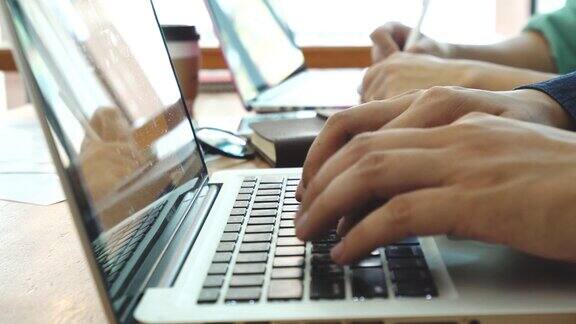 在家工作用笔记本电脑写博客咖啡店里男性的手在敲击键盘