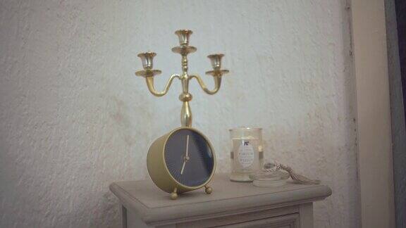 复古烛台支架与一个极简的闹钟在床头柜上