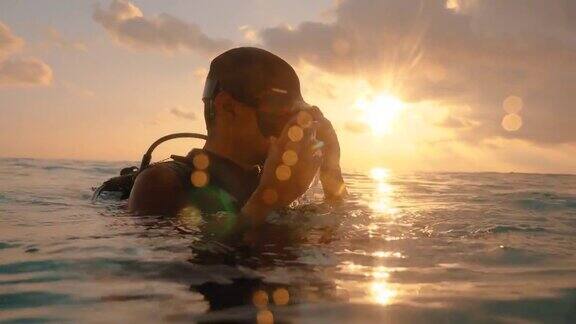 一个戴水肺的潜水员在日落时从水里冒出来的特写镜头