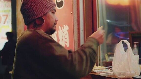 亚洲游客男子晚上在东京街头吃东西