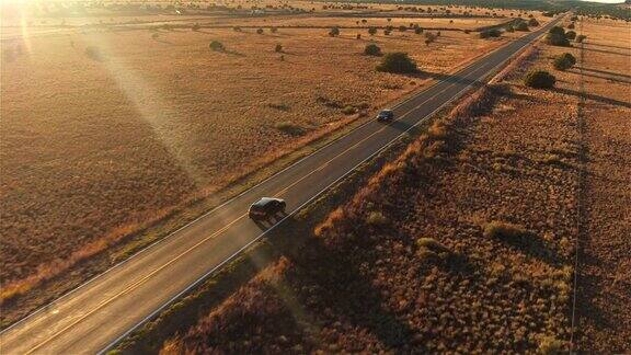 图片:金色的夏日夕阳下一辆黑色SUV行驶在空旷的乡村道路上