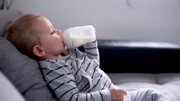 可爱的小男孩躺在床上喝着牛奶
