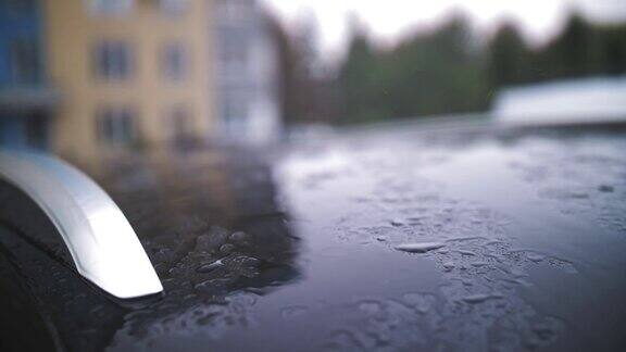 小雨打在车下雨了下雨了雨点一滴一滴地慢慢滴着顺着现代黑色轿车的车顶表面在雨中流淌特写镜头