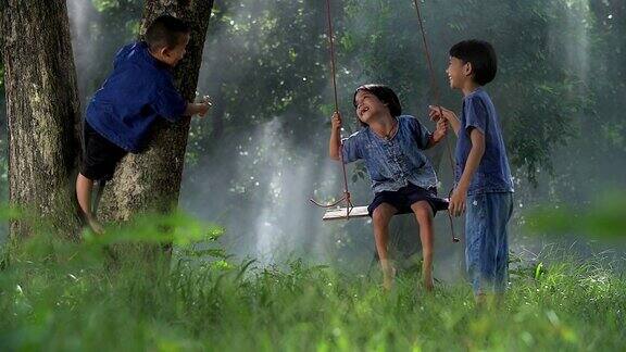亚洲孩子在乡村的树下荡秋千玩得很开心