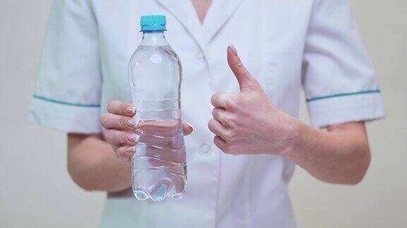 女性营养学家或营养师医生健康生活方式概念-手持一瓶水